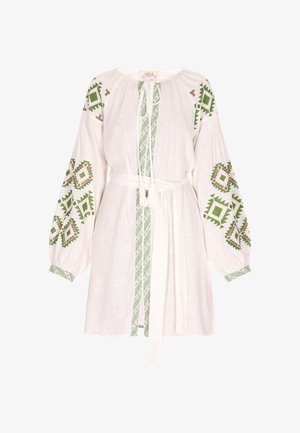 Abito bianco in lino con motivi ricamati in verde e marrone, vita cintrata con cintura e maniche lunghe a sbuffo con decorazioni.