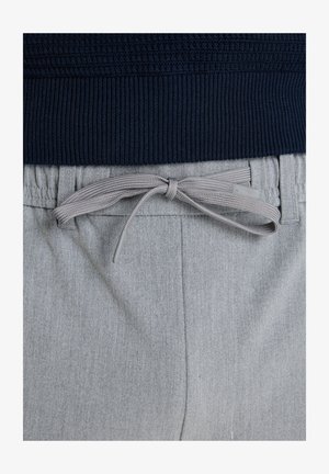 Tume ribiga vöökoht heledest hallist tekstuuriga pükstest üleval. Omab halli paela plastikotsikutega ja küljetaskuid.