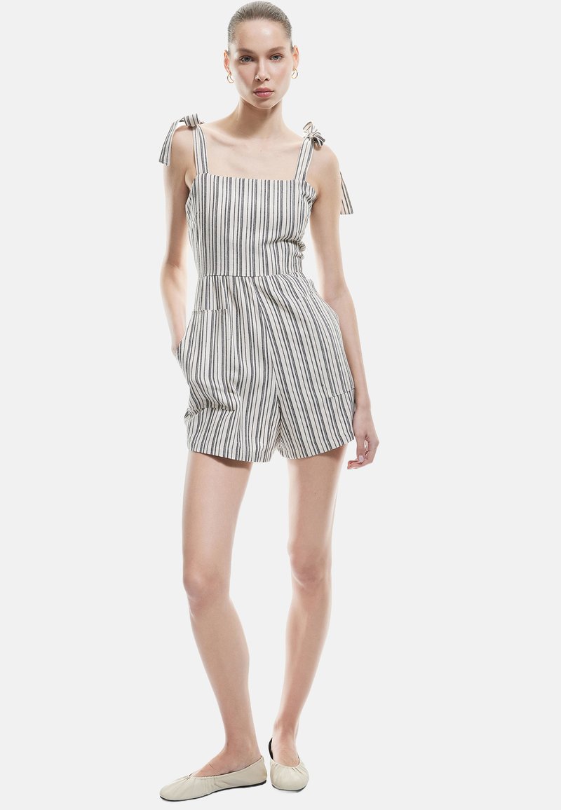 Gestreifter Jumpsuit mit Schulterbindungen, aus leichtem Stoff gefertigt. Hat ein enganliegendes Oberteil, einen elastischen Bund und Seitentaschen. Farben: beige und marineblau.