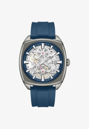 Samodejna ročna ura z modrim silikonskim paščkom, srebrnim kvadratnim ohišjem, vidnimi zobniki ter belimi oznakami ur in kazalci.