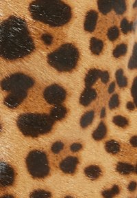 Luipaardprint stof heeft een tan achtergrond met duidelijke zwarte en donkerbruine vlekken. De textuur is glad met een lichte glans.