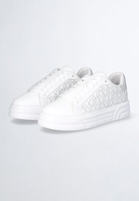Sneakers bianchi realizzati in pelle con un lato strutturato che presenta un motivo delicato, punta arrotondata e suola spessa bianca.