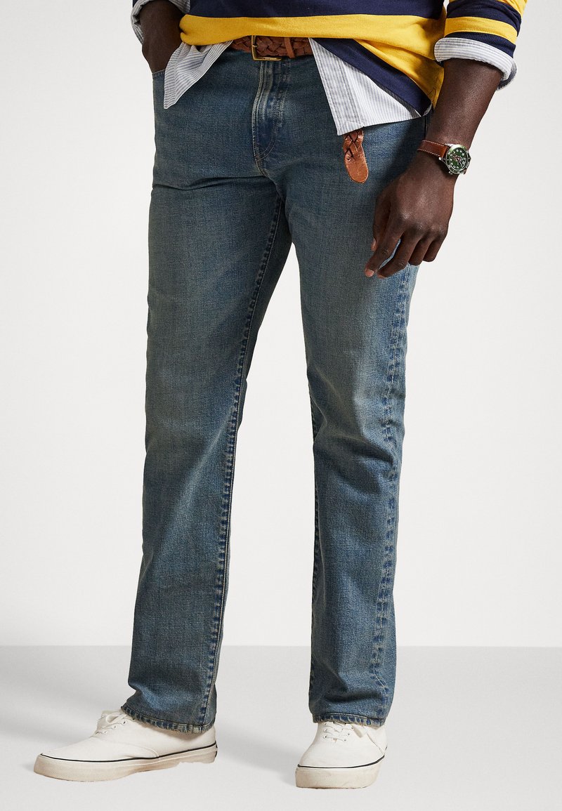 Blå denim jeans med rett benstil, med en falmet tekstur og klassisk femlommers design, kombinert med hvite joggesko.