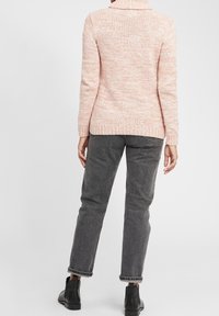 Ljusrosa stickad tröja med hög krage, ribbade ärmslut och nederkant. Matchad med grå tapered jeans och svarta ankelstövlar.