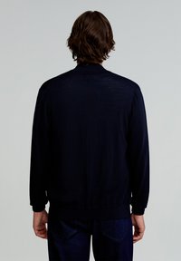 Pulover tricotat albastru cu mâneci lungi, cu mansete și tiv curbate, având o textură netedă și o siluetă simplă, clasică.