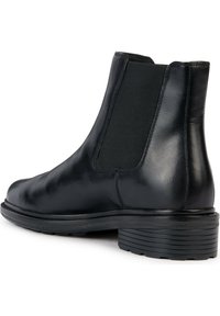 Bota Chelsea de cuero negro con paneles laterales elásticos, punta redondeada y suela de goma texturizada. Acabado suave y diseño minimalista.