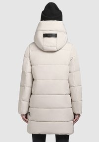 Gevoerde jas in lichtbeige, met een grote capuchon en een horizontaal gestikt ontwerp. Versterkt met een zwart logo label en een lichte glans.