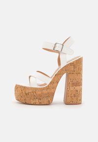 Vita plattformssandaler med korkklackar, med ett band och spänne, slät yta och korsande remmar för stöd.