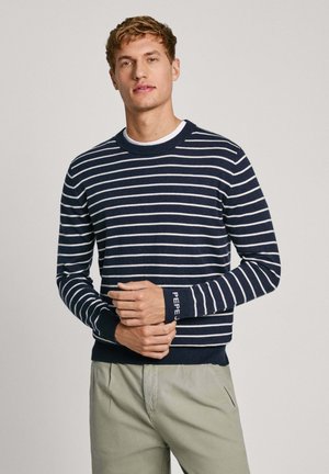 Navy blue and white striped sweater with a round neckline and ribbed cuffs. Features branding on the sleeve and a fitted design.