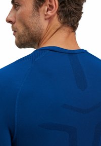T-shirt de sport bleu présentant un design texturé au dos, avec un col rond et des coutures renforcées pour plus de durabilité.
