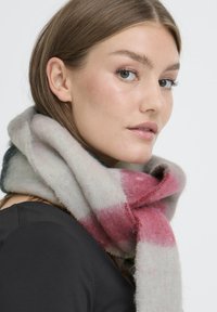 Multicoloreret ternet tørklæde i blød, tekstureret uld. Har lyserøde, grå og hvide nuancer med en løs, draperet stil omkring halsen.