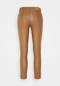 Leggings marrones de corte ajustado, confeccionados con un material elástico. Presentan dos bolsillos traseros y un parche con el logo en la cintura.