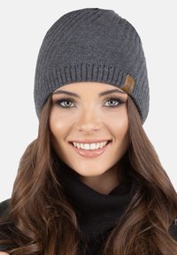 Beanie grigio lavorato a maglia con design a coste e un'etichetta in pelle marrone. Texture morbida con una vestibilità aderente, adatta per l'uso in climi freddi.
