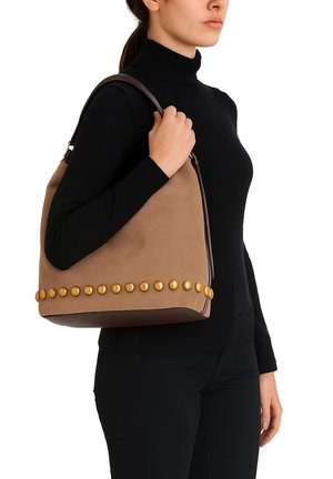 Sac à épaule brun avec des clous ronds dorés le long du bord inférieur, doté d'une poignée en cuir brun et d'un corps en texture douce.