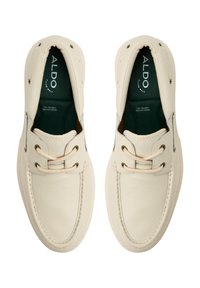 Ljust beige läderskor med rund tå, snörningsdesign och texturerad yta. Har metalöglor och grön foder.