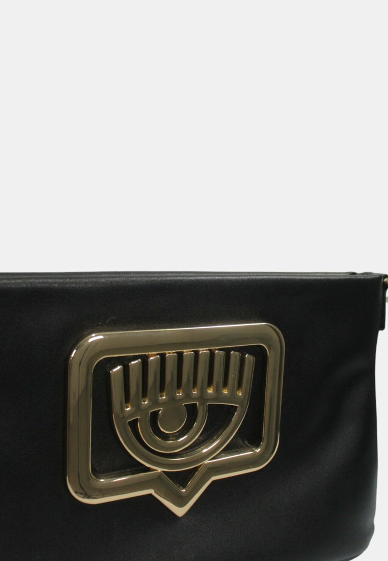 Bolso de mano sintético negro con un destacado acento de hardware en forma de ojo dorado y una textura lisa y suave.