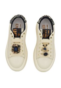 Sneakers color crema con accenti di gemme decorative sui lacci, bordo testurizzato attorno al colletto e un logo sulla soletta.