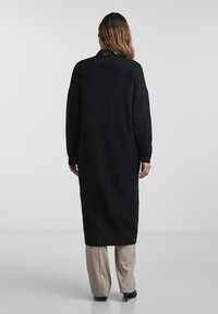 Czarna, długa dzianinowa sukienka o luźnym kroju, z okrągłym dekoltem i opuszczonymi ramionami, charakteryzująca się miękką teksturą i minimalistycznym wzornictwem.