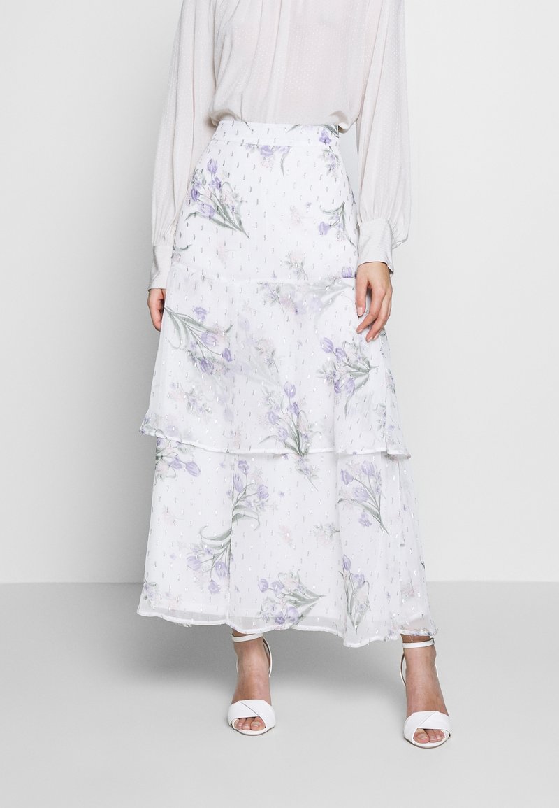 Weißer, fließender Maxirock mit gestuften Lagen und floralem Muster in Lila und Grün. Durchsichtige Textur mit dezenten Verzierungen überall.