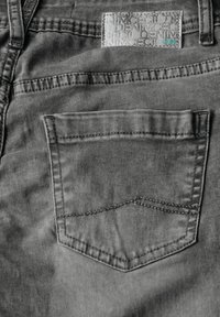 Jeans in denim grigio con una tasca posteriore caratterizzata da un'elegante decorazione con cuciture e una patch con logo sopra, che enfatizzano una texture liscia e uno stile casual.