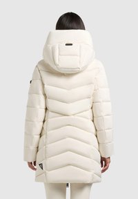 Bundička na zimu v smotanovej farbe s kapucňou, s chévronovým prešívaním, hladkou textúrou a logom na okraji.