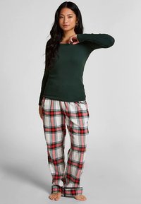 Groen top met lange mouwen gecombineerd met geruite pyjamabroek in rood, zwart en wit in een geruit patroon. Zacht materiaal, losse pasvorm.