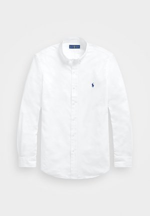 Chemise blanche à manches longues avec boutons, col boutonné et petit logo bleu brodé sur la poitrine gauche.