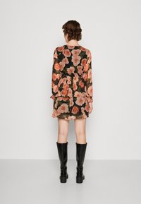 Blommig klänning i genomskinlig svart tyg, med stora persikorosor, långa ärmar, volangkjol och elastisk midja. Matchas med knähöga svarta stövlar.