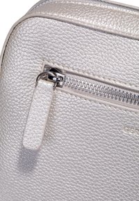 Silberne Kunstledertasche mit strukturiertem Oberflächen, Reißverschlussverschluss und metallischen Hardwareakzenten. Kleiner Lederreißverschluss-Anhänger angebracht.