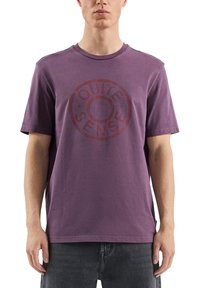 Fioletowa bawełniana koszulka z okrągłym nadrukiem "QUIT SENSE" w ciemnoczerwonym kolorze. Krótkie rękawy i okrągły dekolt, o luźnym kroju.