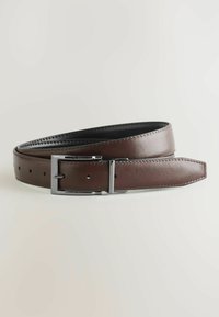 Ceinture en cuir brun enroulée avec une boucle métallique rectangulaire argentée et plusieurs trous pour un ajustement de taille sur fond clair.