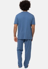 Sininen puuvillainen pyjama-setti, joka sisältää lyhythihaisen t-paidan ja väljän housut. Silkkisen pehmeä pinta ja yksinkertainen muotoilu.