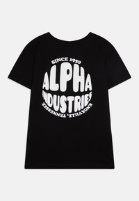Juodas medvilninis marškinėliai su dideliu baltu apvaliu logotipu, kuriame yra tekstas "ALPHA INDUSTRIES" ir "SINCE 1959", apvaliu kaklu ir trumpomis rankovėmis.