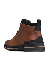 Bruine leren enkelboot met zwarte accenten, ronde neus, textuurzool en gaatjes voor veters. Geniete ontwerp aan de zijkant.