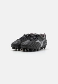 Crampons de football noirs avec un dessus en cuir texturé, des coutures surélevées et des accents argentés. Dotés de pointes en caoutchouc pour une traction sur surfaces herbeuses.