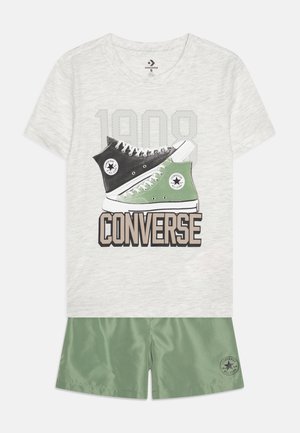 Szara koszulka z krótkim rękawem z grafiką czarno-zielonego trampka Converse oraz napisem "1908 CONVERSE"; w zestawie z zielonymi szortami.
