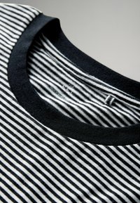 Maglietta a maniche corte a righe bianche e nere con scollo rotondo nero solido, caratterizzata da sottili e uniformi linee orizzontali su tutto il tessuto.