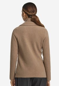 Brun texturerad tröja med sjalkrage, med en figursydd design och långa ärmar, sedd bakifrån. Slät tygfinish.