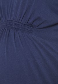 Närbild av marinblått tyg med samlat stygn som skapar små veck och textur.