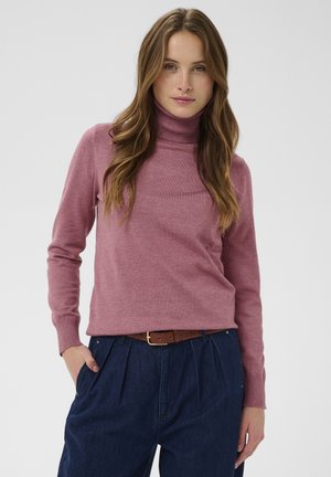 Pink turtleneck sweater with long sleeves, made of a soft material. Paired with high-waisted dark denim trousers and a brown belt.
