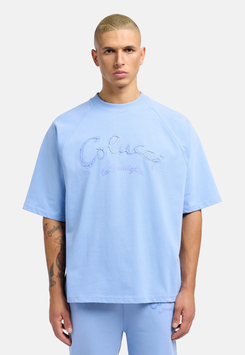 Light blue short-sleeve sweatshirt with a crew neck, featuring embroidered text "Colucci la Famiglia" in varying shades of blue.