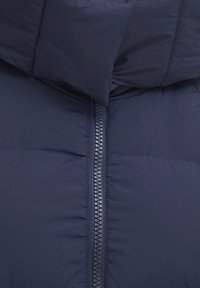 Námořnická puffer bunda s vysokým límcem, prošívanou texturou a předním zipem s kontrastním poutkem. Měkká, lehká tkanina.