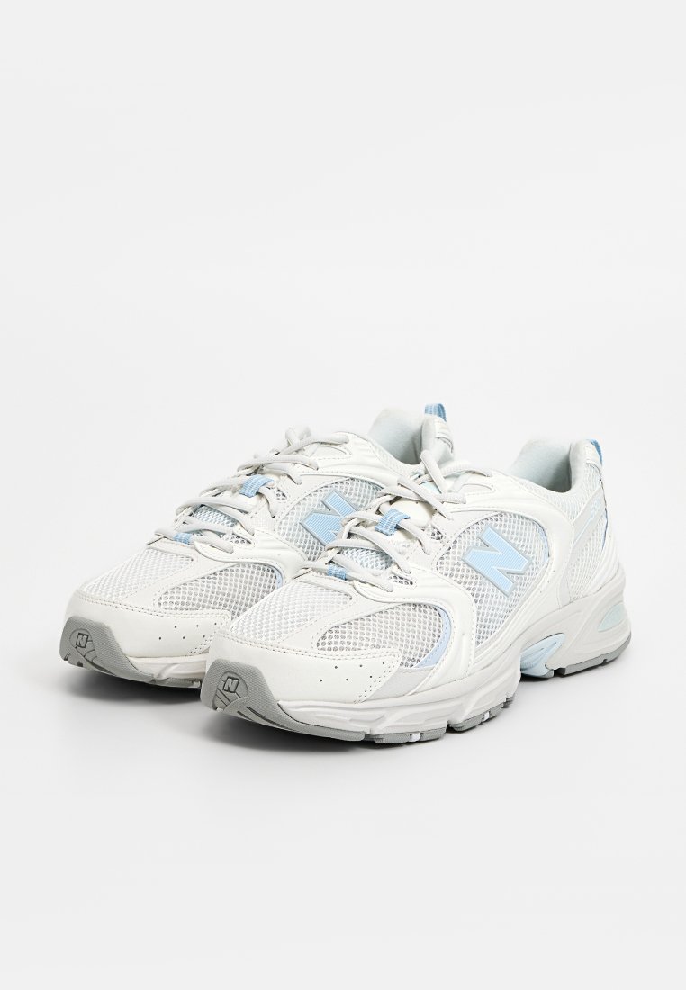 Scarpe da ginnastica bianche e azzurro chiaro con tomaia in rete, colletto imbottito e suola testurizzata. Presentano un grande logo "N" sui lati.