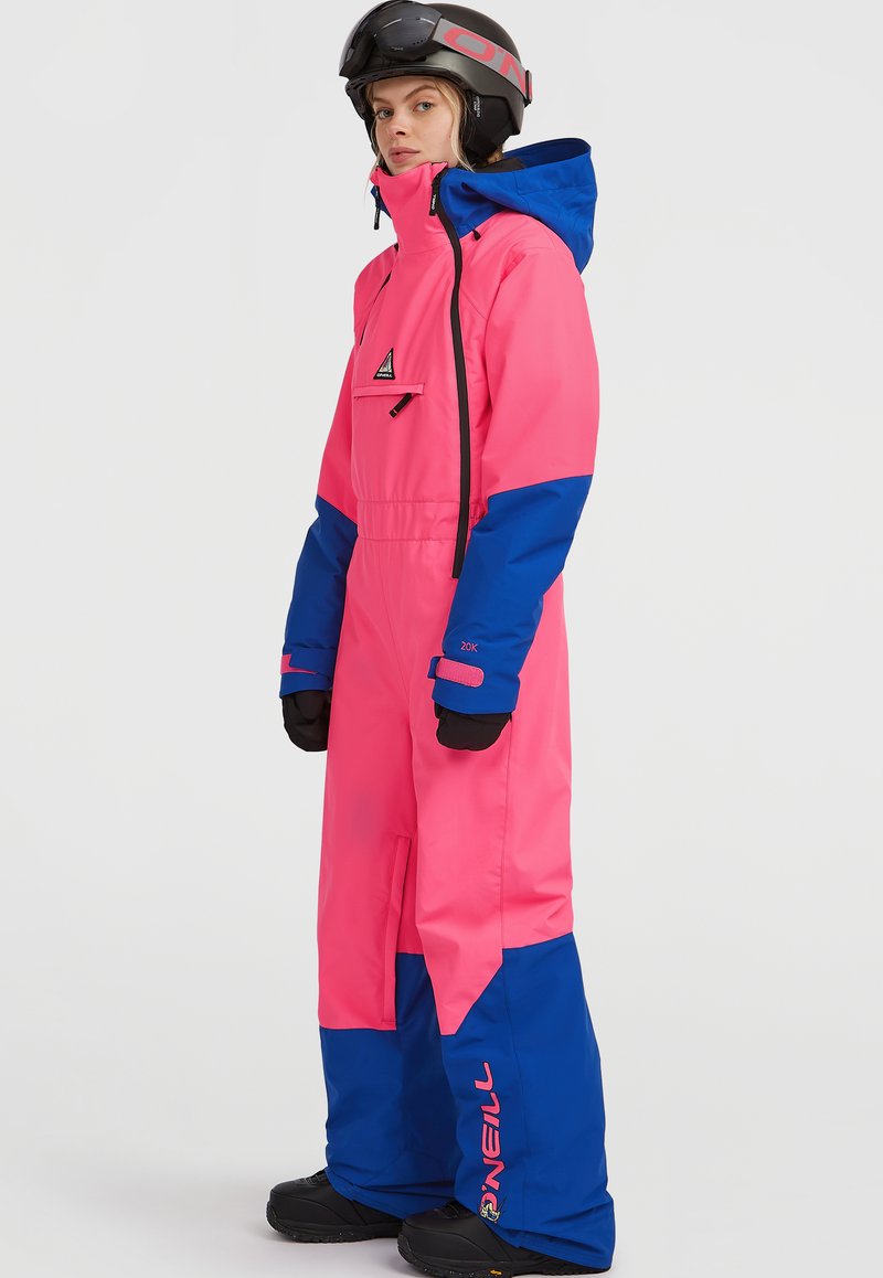 Helderroze en blauwe sk Suit gemaakt van waterdicht materiaal, met een capuchon, een voorzak en versterkte manchetten. Merkl logo zichtbaar op het been.