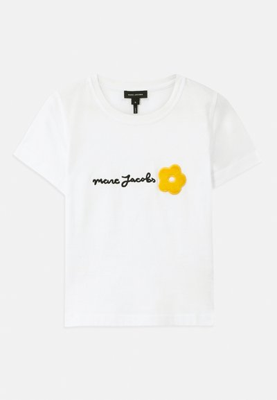 Camiseta blanca de algodón de manga corta, con texto en cursiva negro "marc Jacobs" y un aplique de flor de fieltro amarillo en el frente.