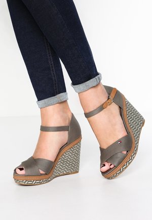Gray wedge sandals with crisscrossed straps, a peep toe, and woven detailing on the wedge heel. Brown accents near the sole.