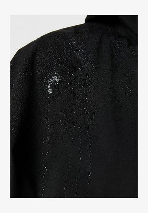 Tissu noir avec des gouttes d'eau perlées et s'écoulant sur la surface, mettant en avant ses propriétés hydrofuges.