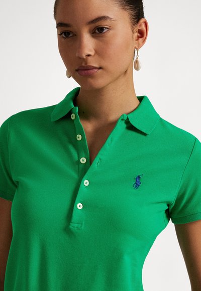 Grønn poloskjorte laget av teksturert bomull, med klassisk krage, knapper foran og en blå brodert logo på brystet.