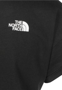 Černé bavlněné tričko s kulatým výstřihem, na levé horní straně je bílé logo značky The North Face.