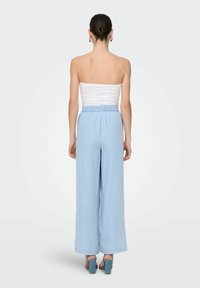 Pantalons larges bleu clair avec une taille élastique, associés à un haut ajusté sans bretelles blanc, présentant une texture lisse et une coupe décontractée.